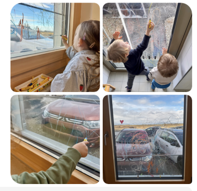 Kinder zeichnen mit verschiedenen Farben an einem Fenster und beobachten die Außensicht.