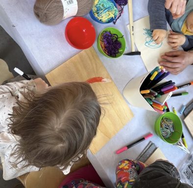 Kreative Kinder, die an einem Tisch mit Farben und Bastelmaterialien arbeiten.