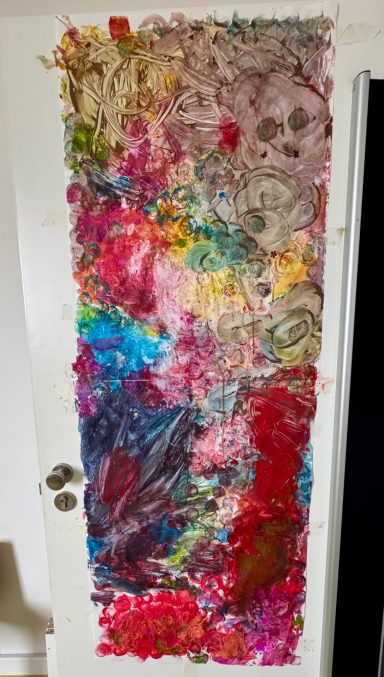 Bunte, abstrakte Kunstinstallation aus Farben und Texturen auf einer Tür.