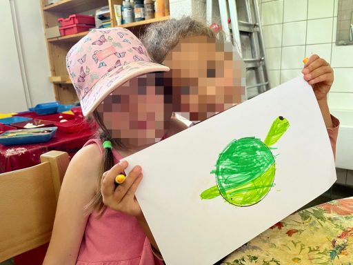 Zwei Kinder halten ein buntes Bild einer Schildkröte in den Händen.