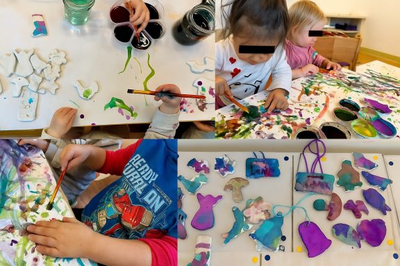 Kinder beim Malen und Basteln mit bunten Farben und Materialien auf einem Tisch.