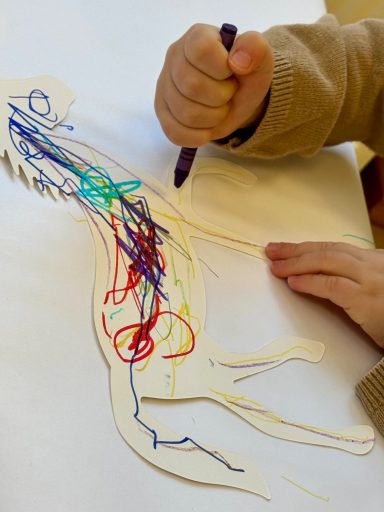 Eine hand kritzelt bunte Linien auf eine Zeichnung eines Pferdes.