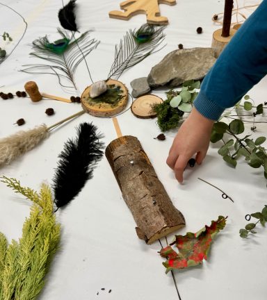 Anordnung aus Naturmaterialien wie Blättern, Federn und Holz auf einem Tisch.