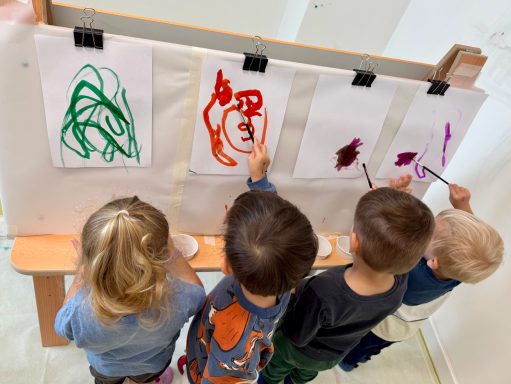 Kreativität an der Staffelei Vier Kinder malen an einer Wandtafel mit bunten Farben auf Papier.
