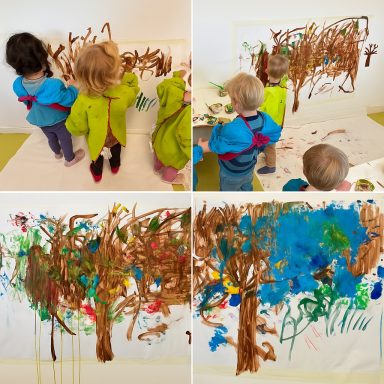 Kinder malen gemeinsam bunte Bäume auf große Papierblätter.