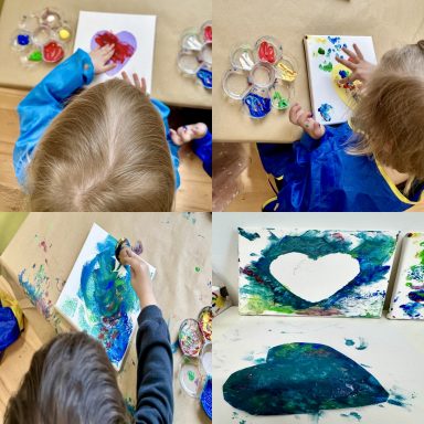 Kinder malen mit Farben und gestalten ein Herz auf Papier.